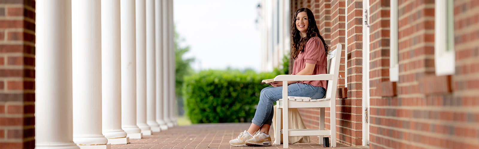 dallas college student sitting on bench outside with book