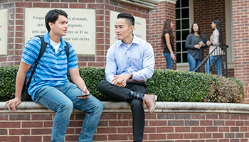 international students sitting in front of DBU globe statue