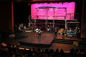 A stage with people performing and a large screen displaying visuals.