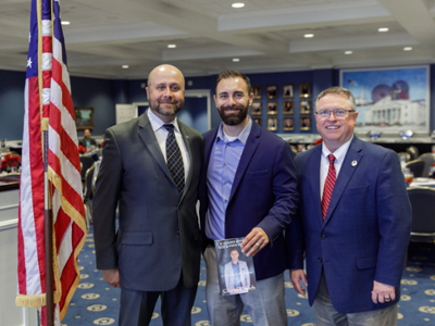 three men standing in Sadler Hall at the veterans day reception