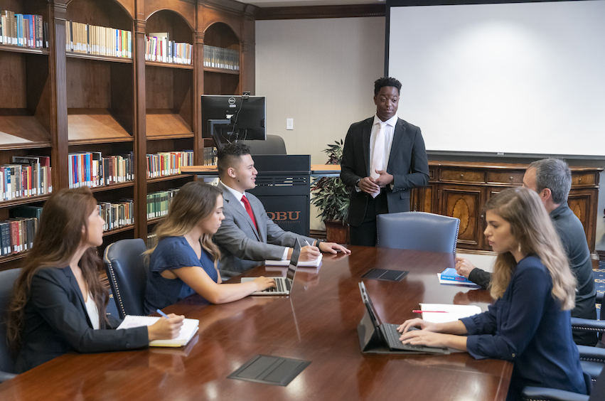 graduate students in Dallas, Texas sitting around a table learning in class 