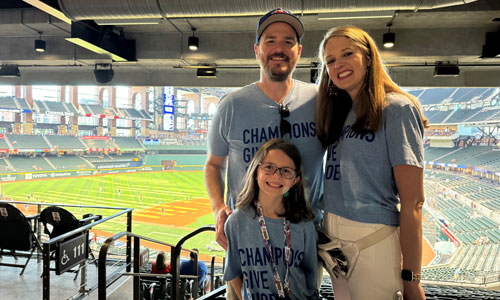 Family at baseball stadium wearing matching shirts.