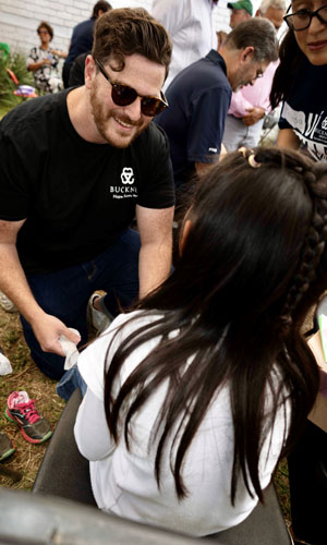 Volunteer fitting shoes for child at event.