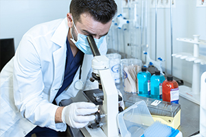 picture of a man looking at a microscope in a lab